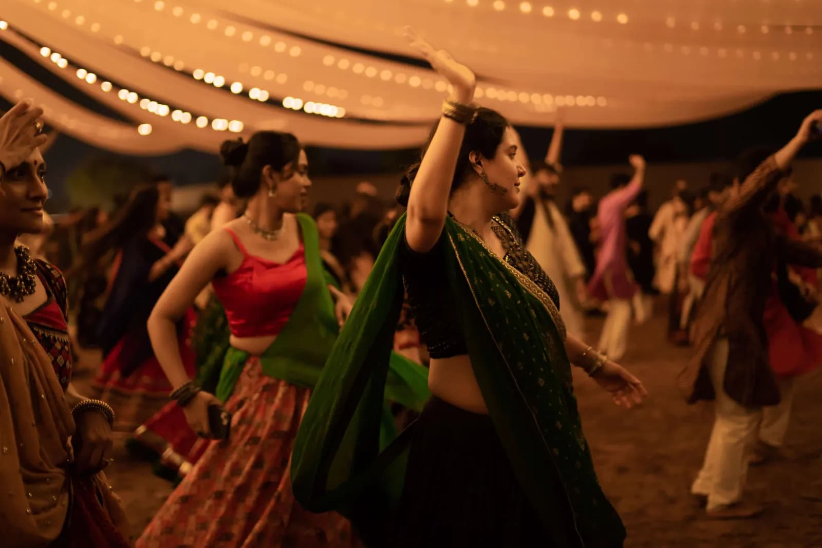 Dancers with arms raised beneath the fabric canopy
