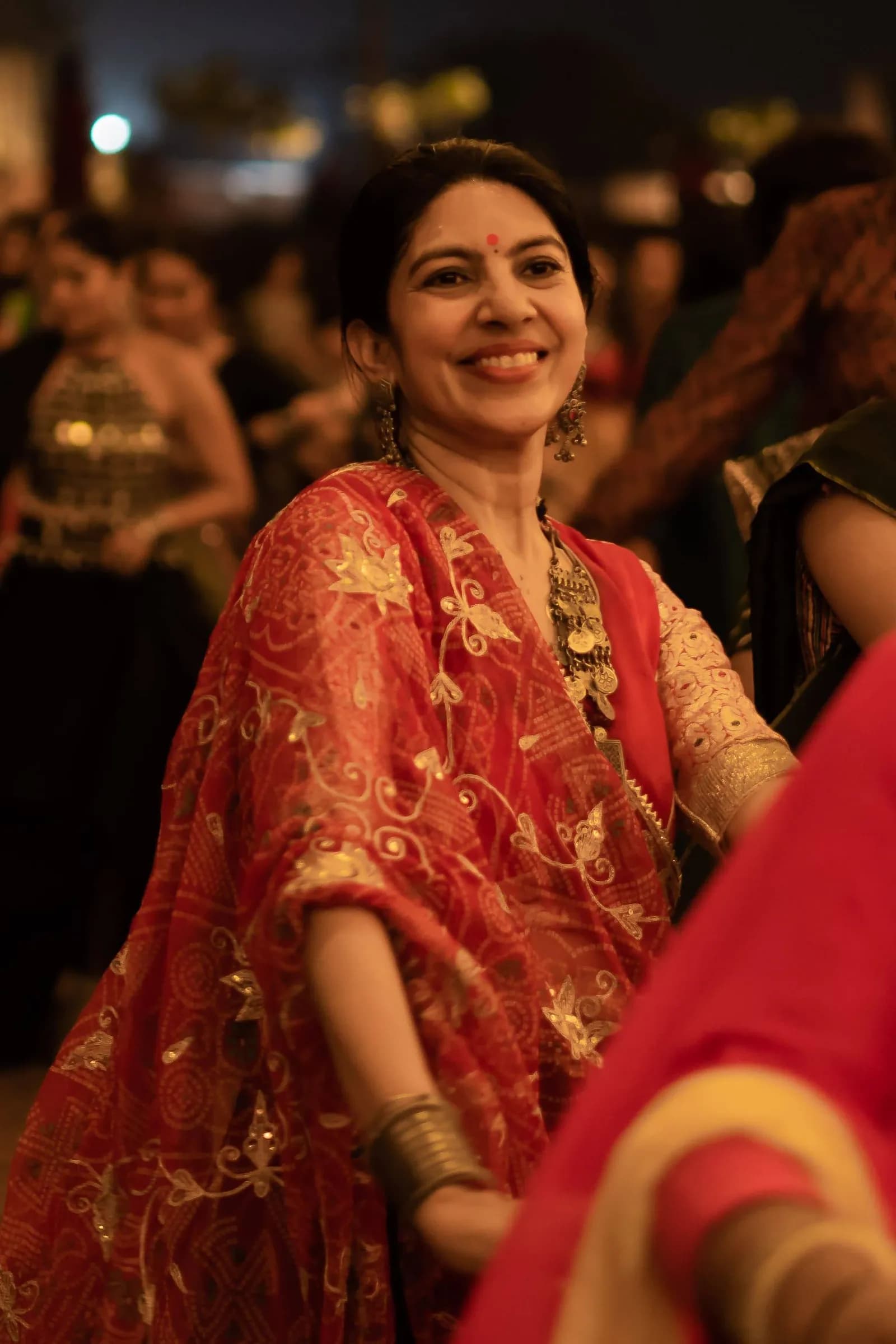 A dancer in red and gold with hands raised