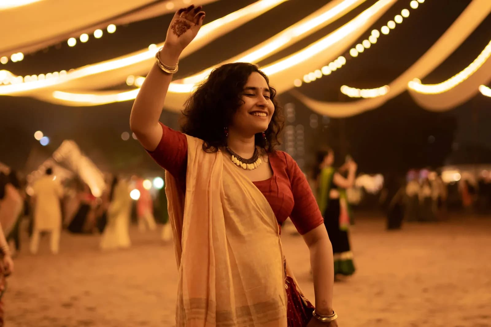 A dancer in white and gold beneath strings of lights