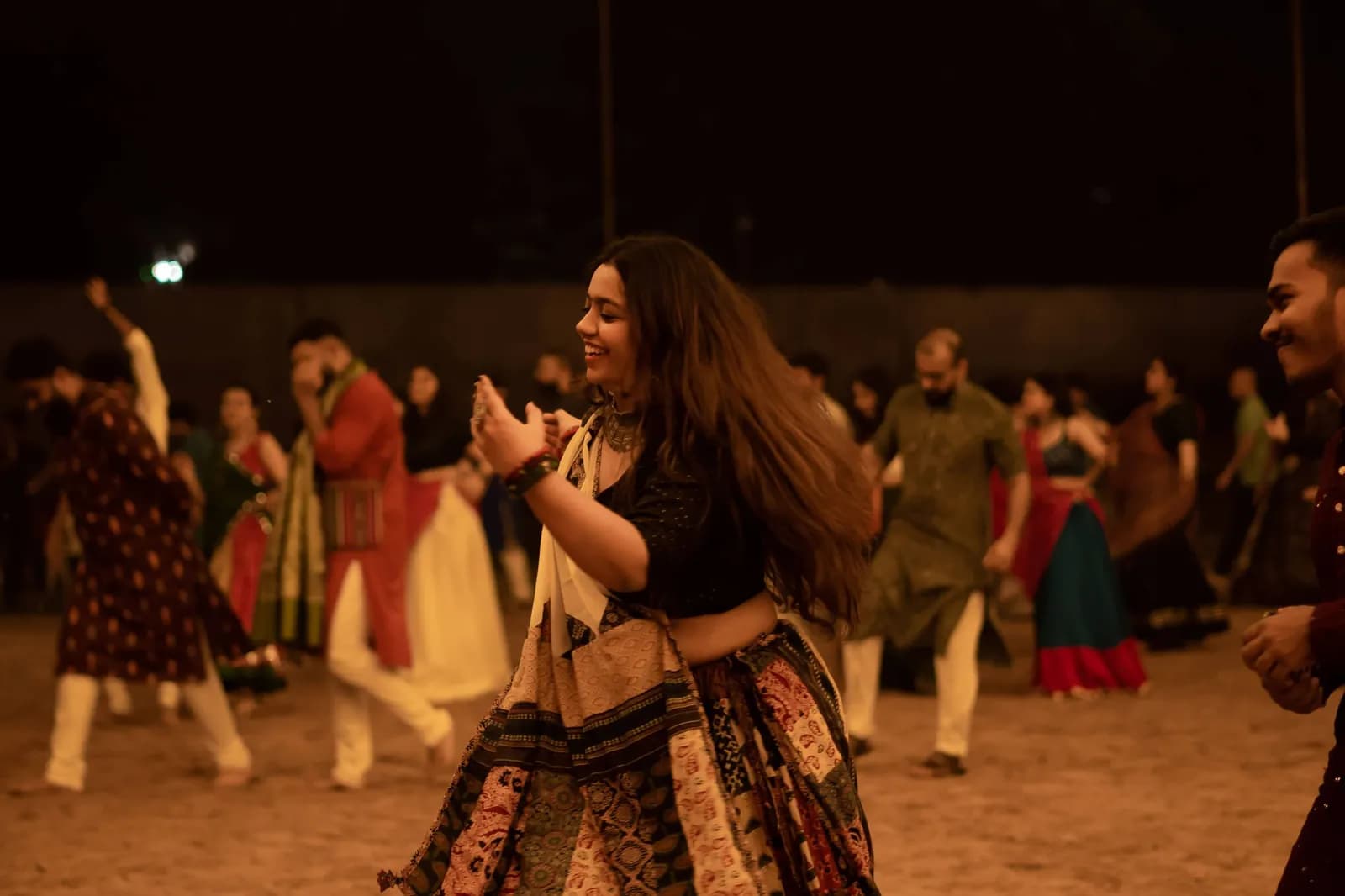 Dancers on the ground at night, one mid-step in the foreground