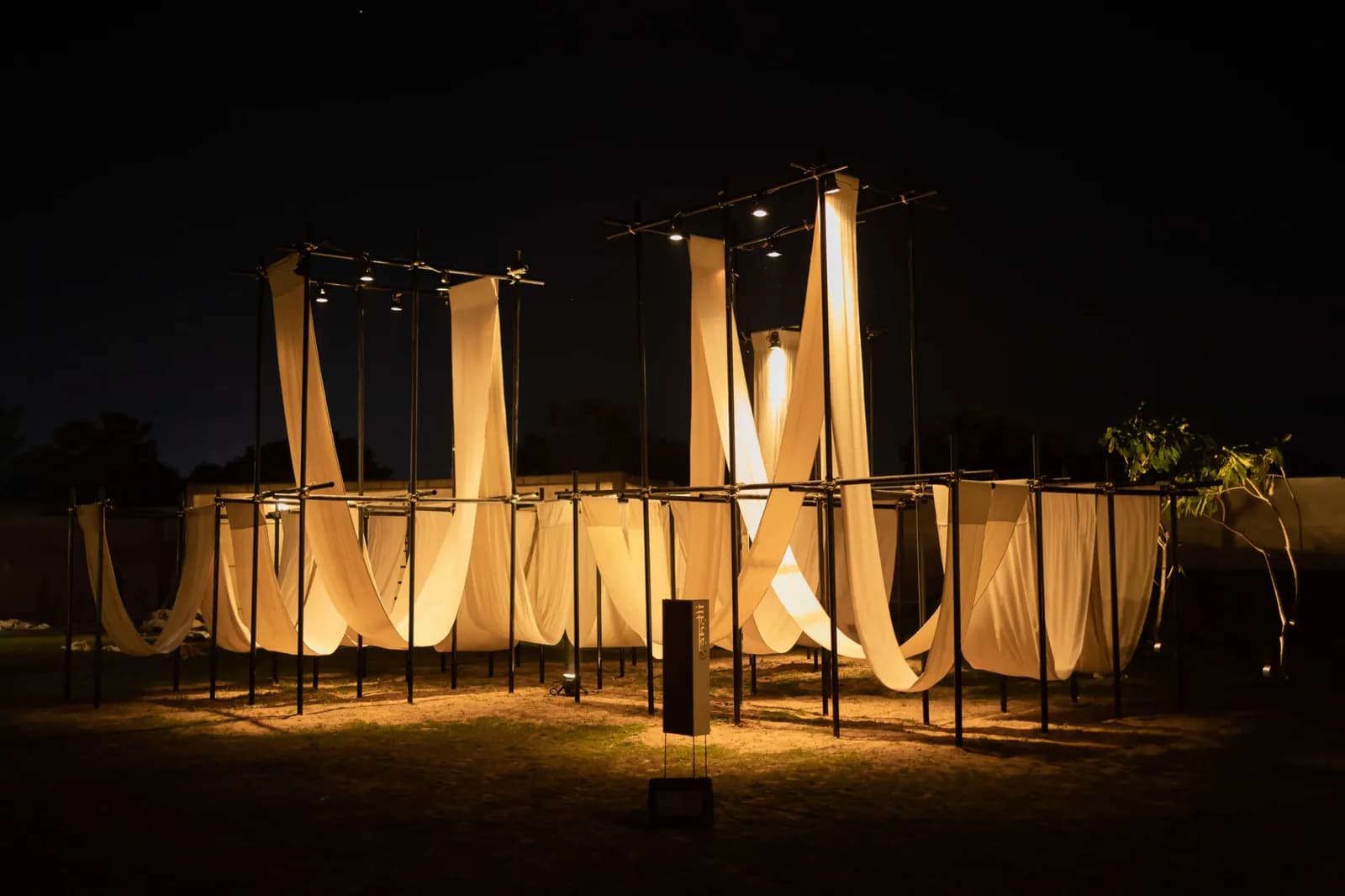 A lit gateway structure hung with fabric panels