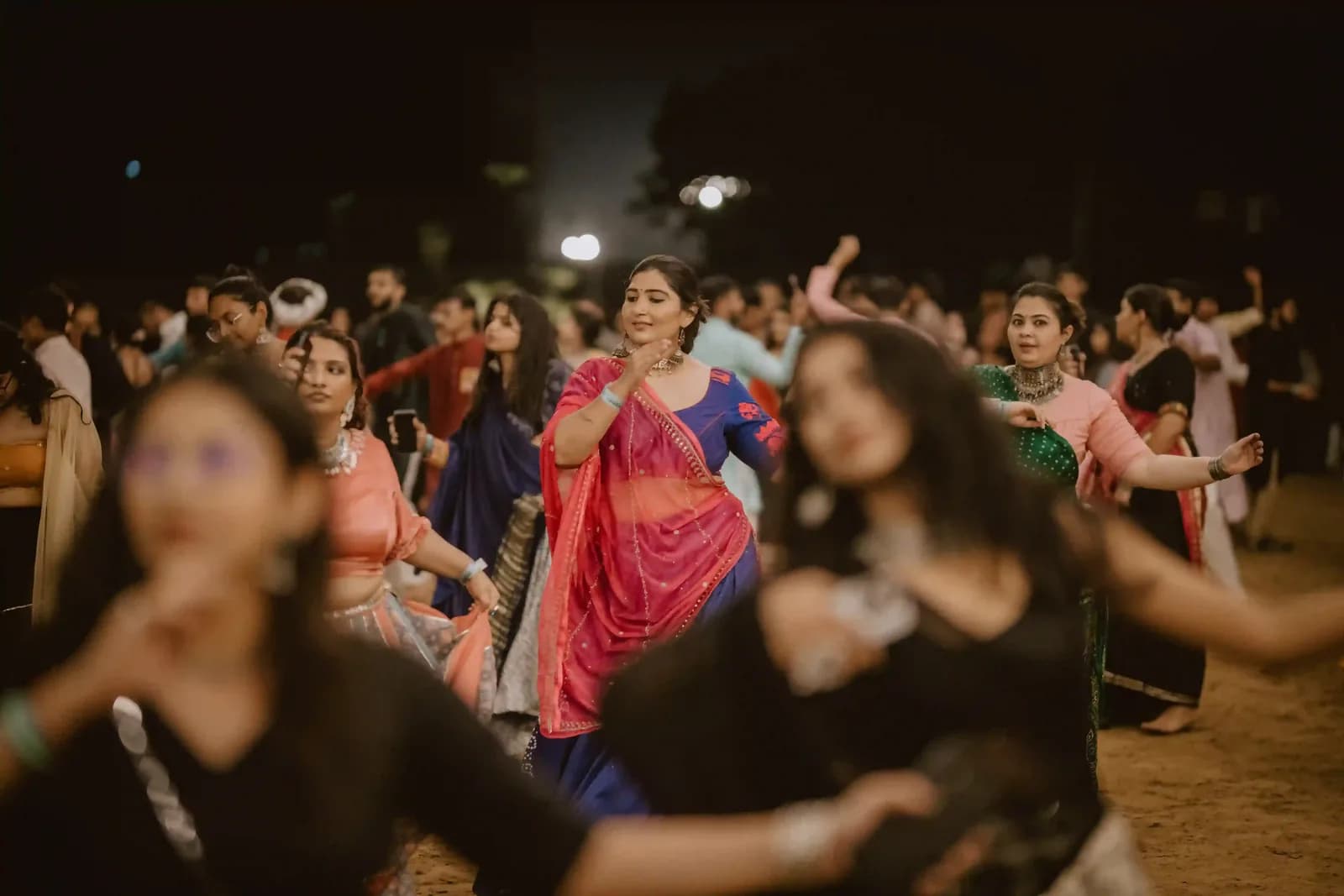 Dancers in traditional dress performing garba on an open ground at night